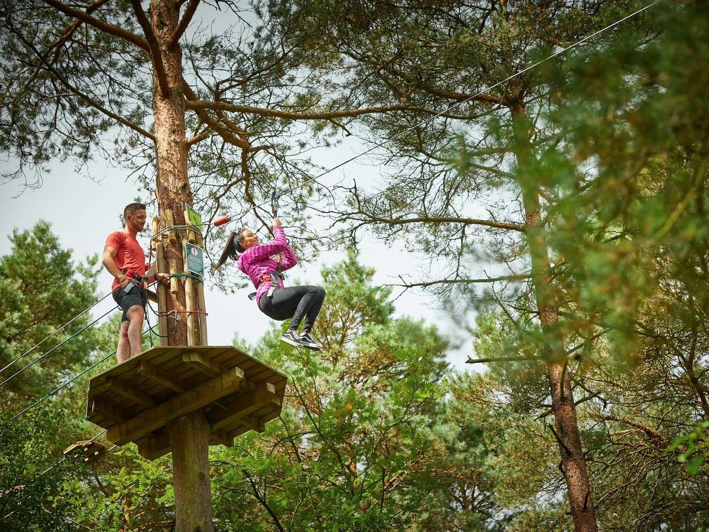 A person on a zip wire while another person watches from a platform.