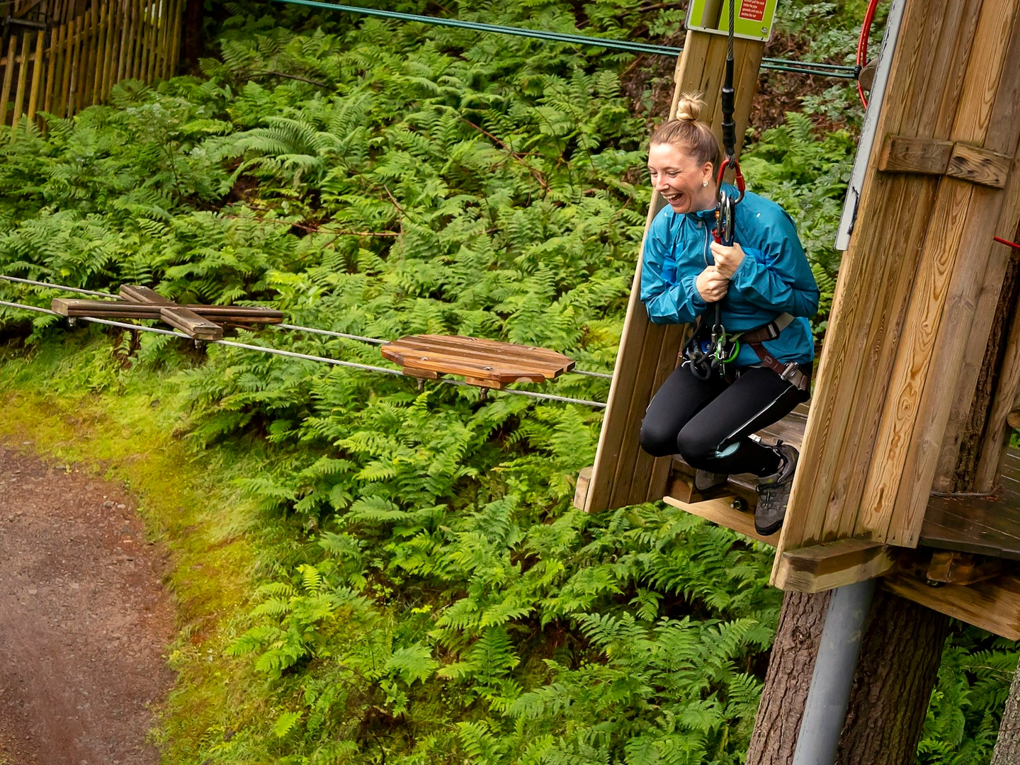 A person grinning as they get ready to swing from a high ropes course.