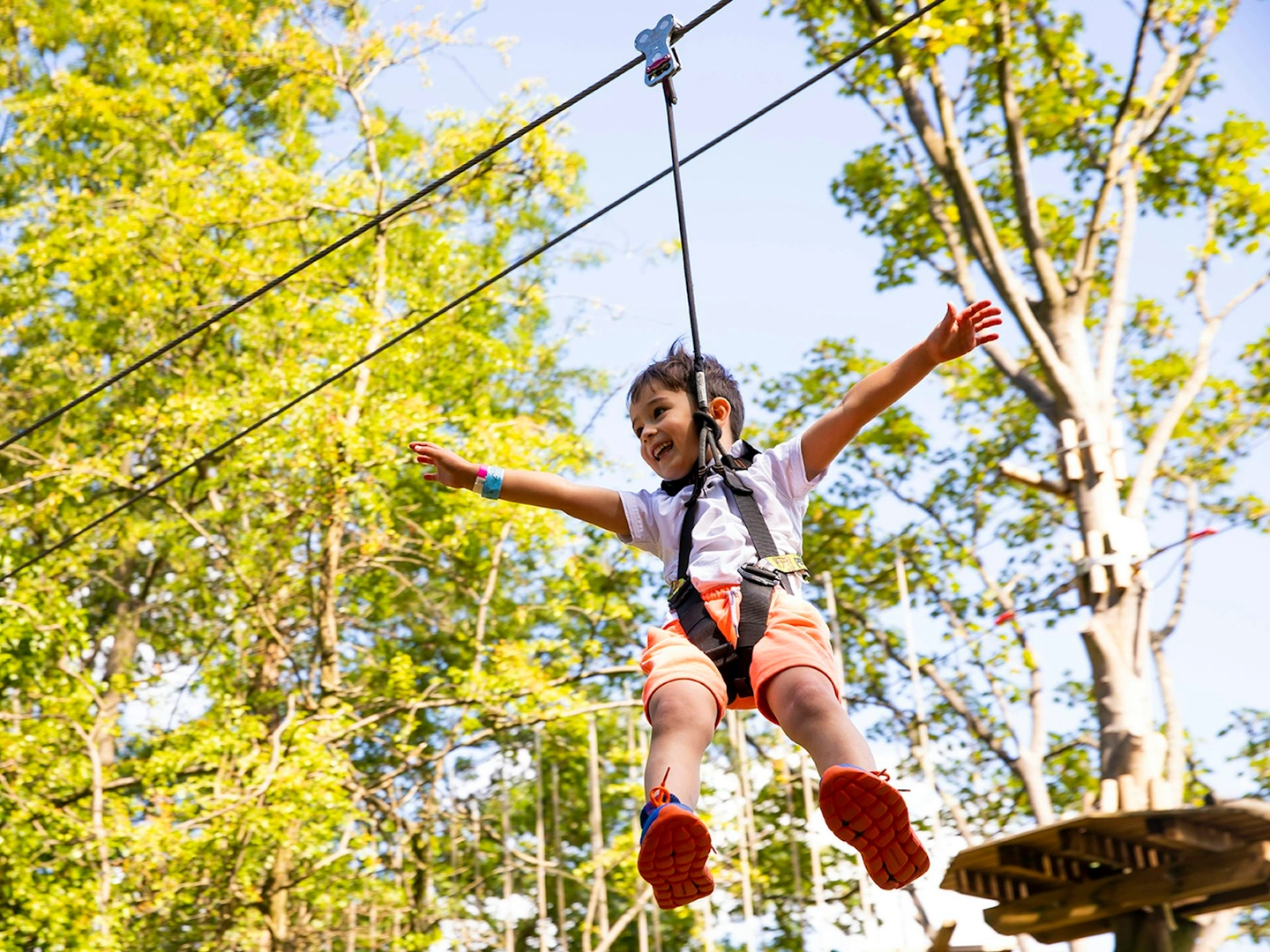 Young person on a zipline while smiling.