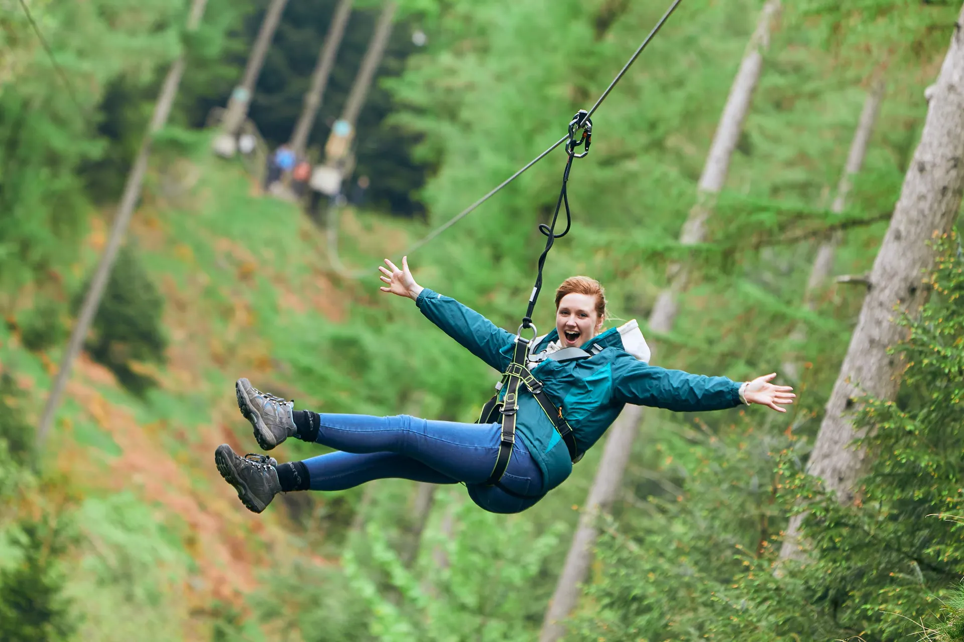 Person grins with their arms wide on a zip wire.