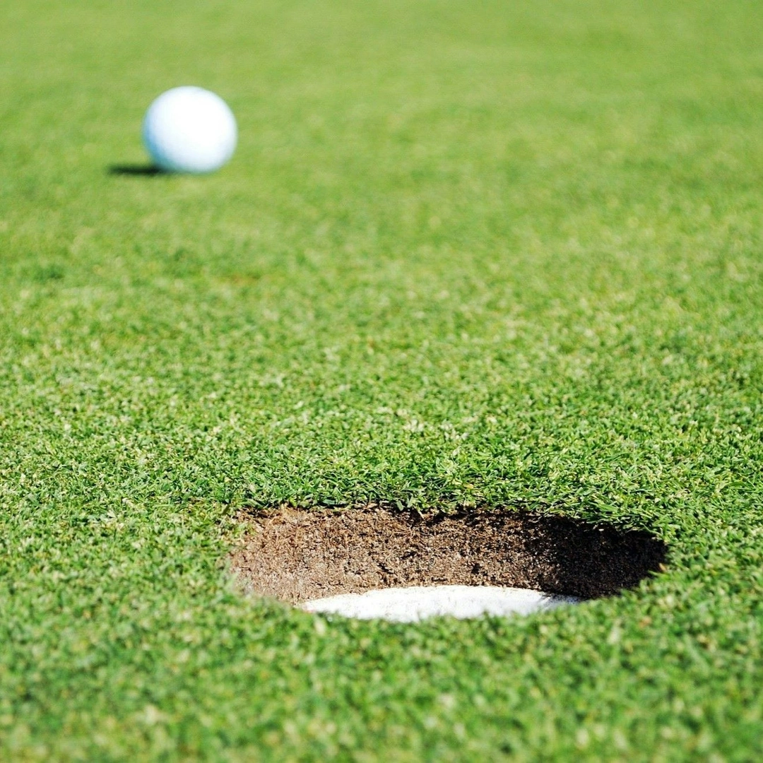 A golf ball on a green rolling towards the hole