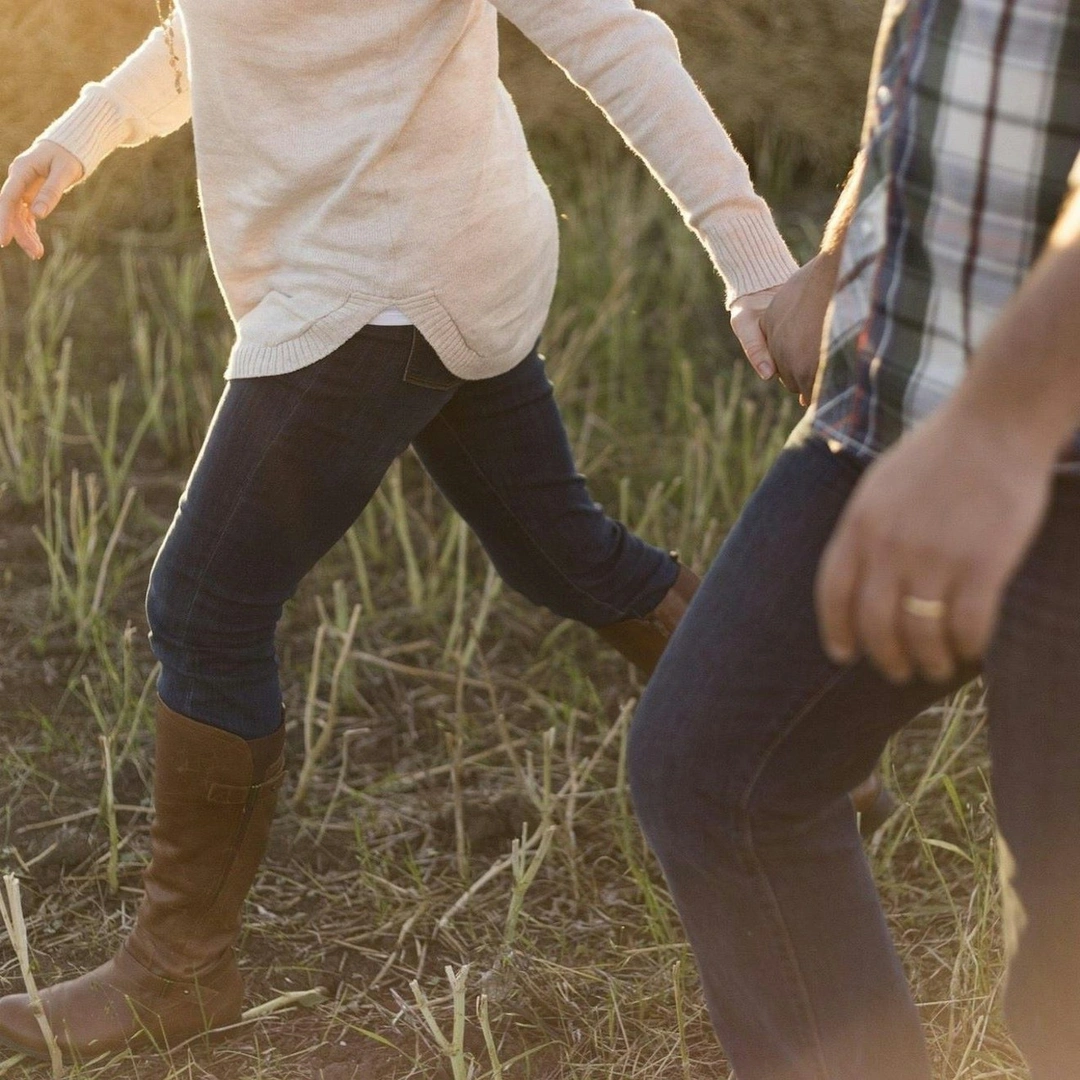 A couple hold hands as they stroll in the countryside